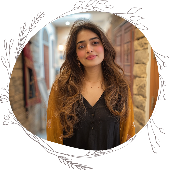 Emily wearing a black dress with a yellow scarf, smiling in a cozy, beautifully decorated indoor setting.